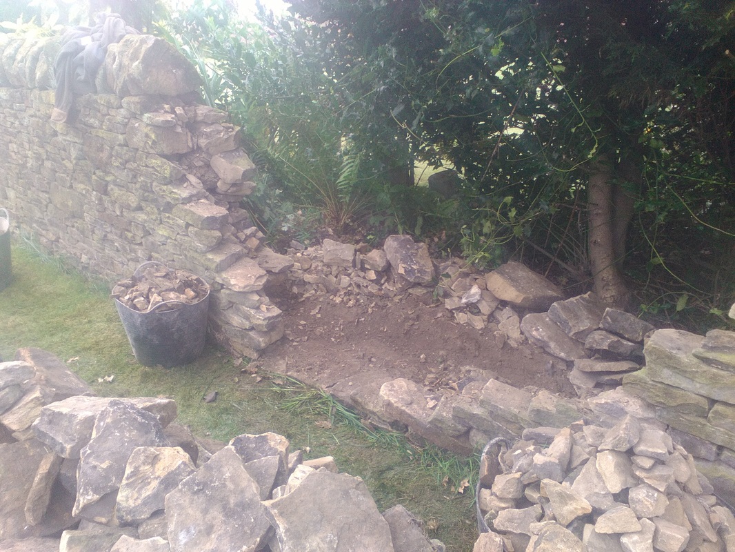 collapsed section of wall stripped back in a large v shape back to sound wall