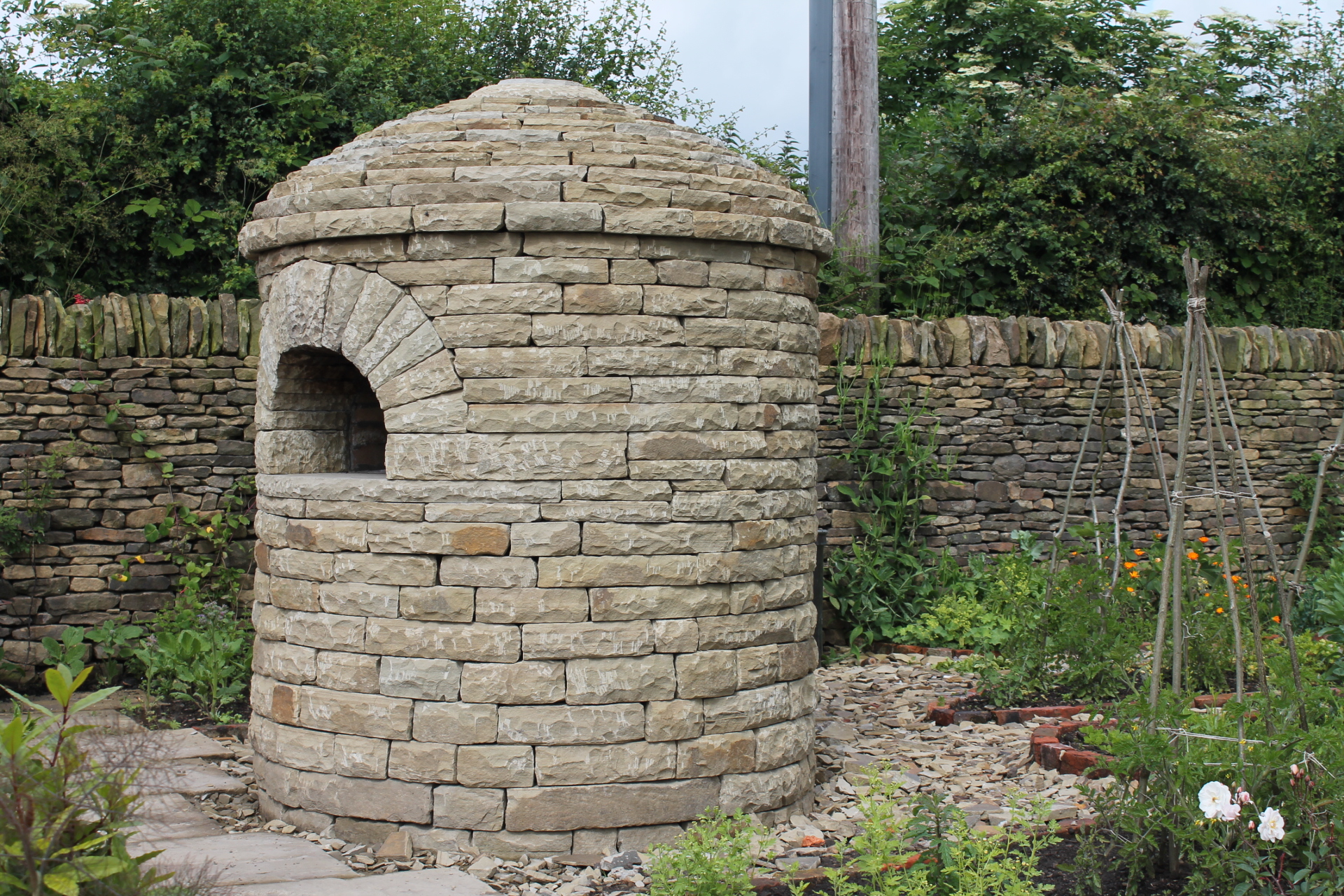 The completed stone pizza oven standing in a garden